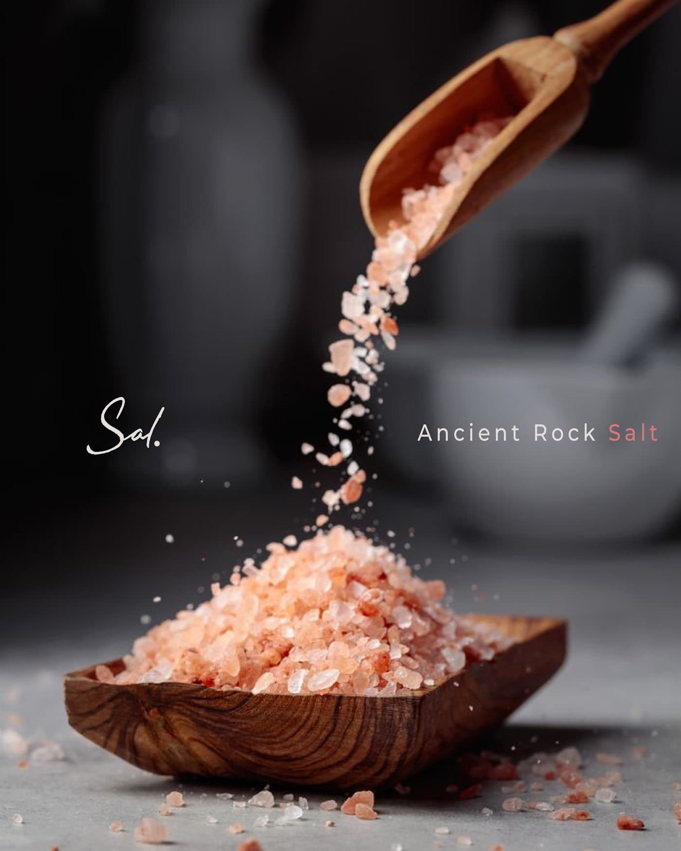 Pink rock salt poured from a wooden scoop
